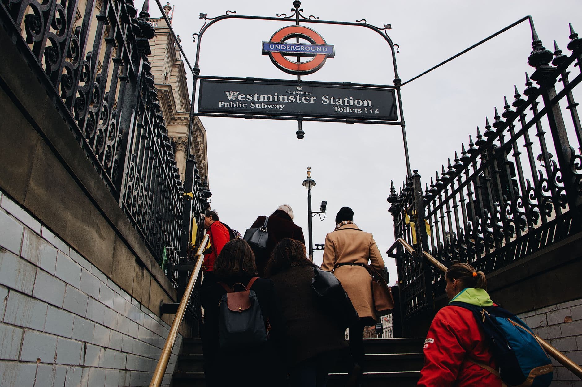 Low angle of anonymous people walking up stairs while leaving subway station on gray day in city