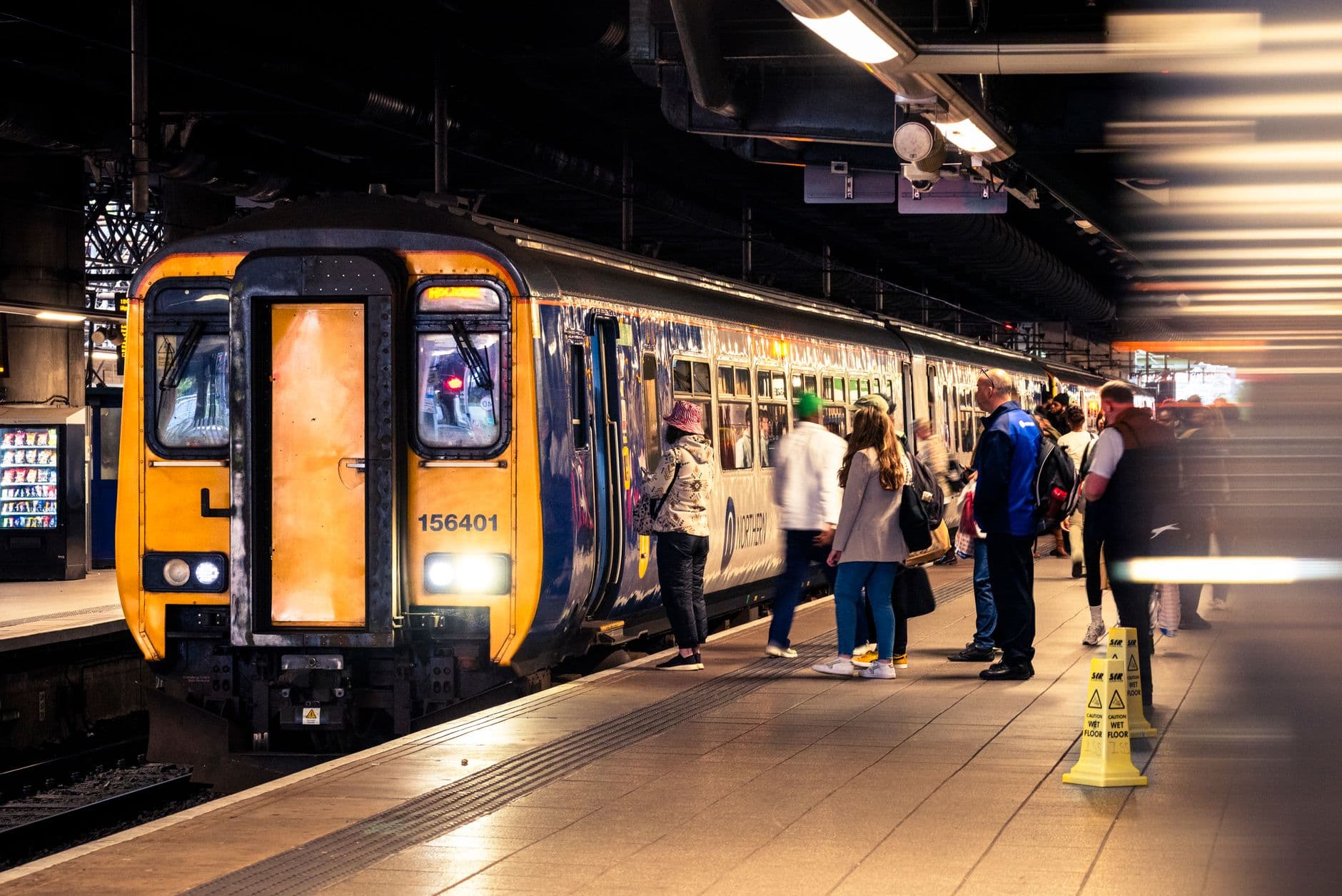 Passengers boarding a train at a bustling indoor station in England.